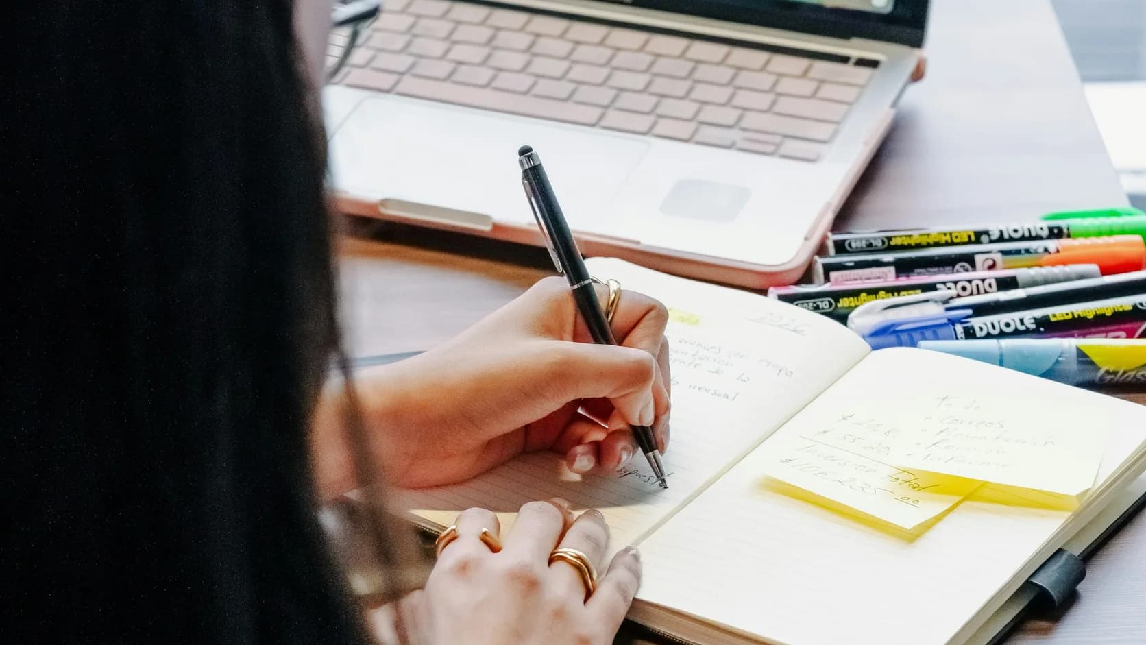 A writer comparing handwritten notes with work on a laptop