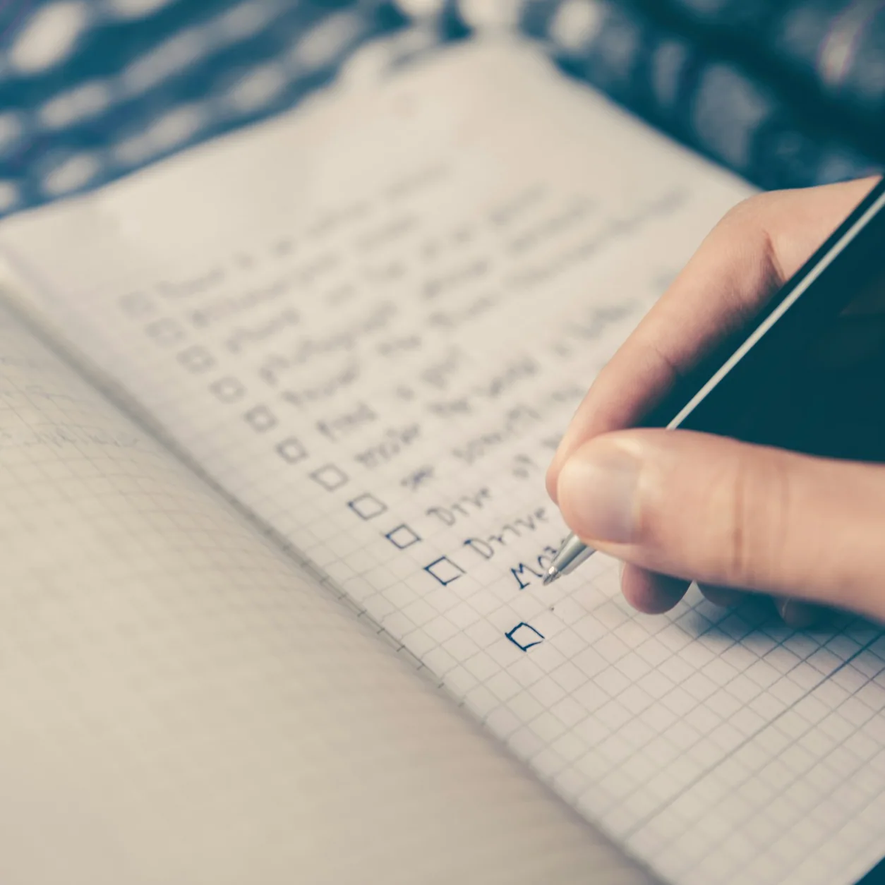 Uma mão escrevendo uma lista de verificação em um caderno