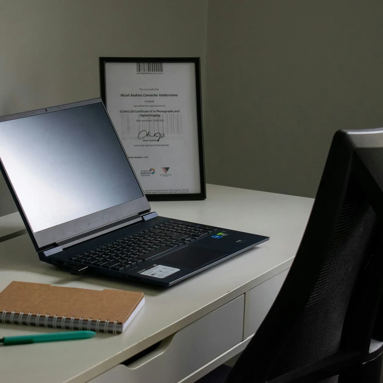 A laptop, notebook, and pencils arranged on a desk