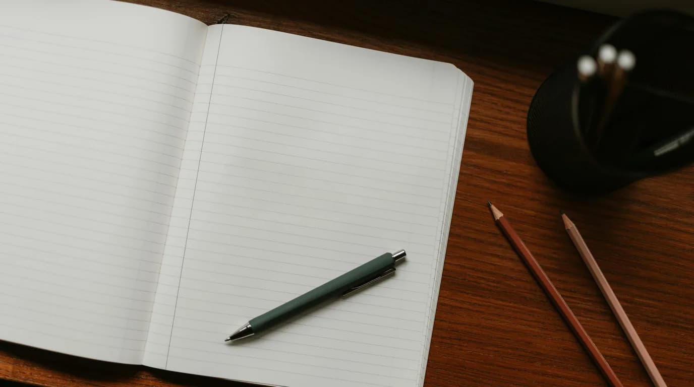 An open notebook and writing tools on a wooden desk